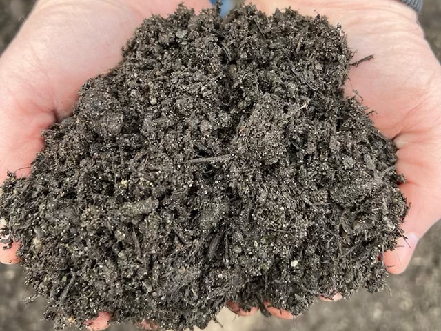 Two hands holding 3-way premium topsoil
